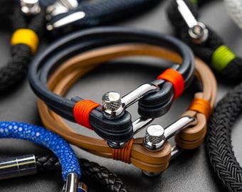 May include: Close-up of three leather bracelets with silver clasps. The bracelets are in shades of brown, black, and blue.