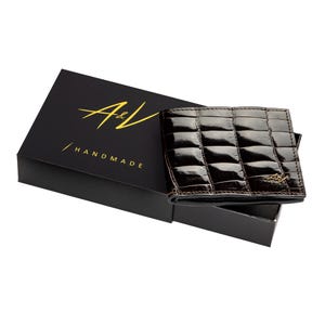 May include: A brown leather wallet with a crocodile pattern and gold A&V Handmade logo. The wallet is in a black box.