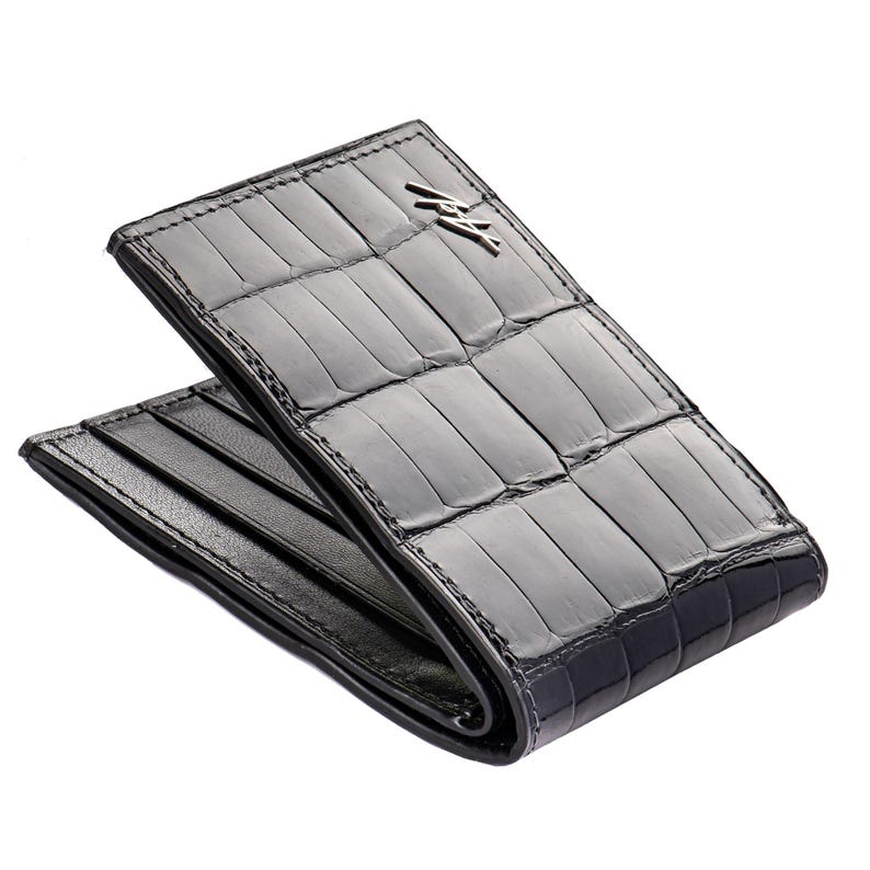 May include: A black alligator leather wallet with a silver logo. The wallet is folded in half and has a textured surface.