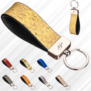 May include: A yellow and black leather key chain with a silver ring and a silver tag with the word "Not" on it. The key chain is made of genuine python skin. There are nine other key chains in different colours in the background.