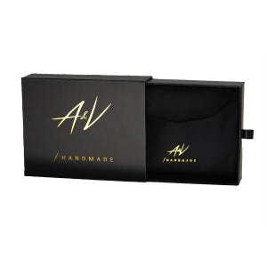 May include: Black box with a gold A&V logo and the text "HANDMADE". The box is open and the inside is lined with black fabric.