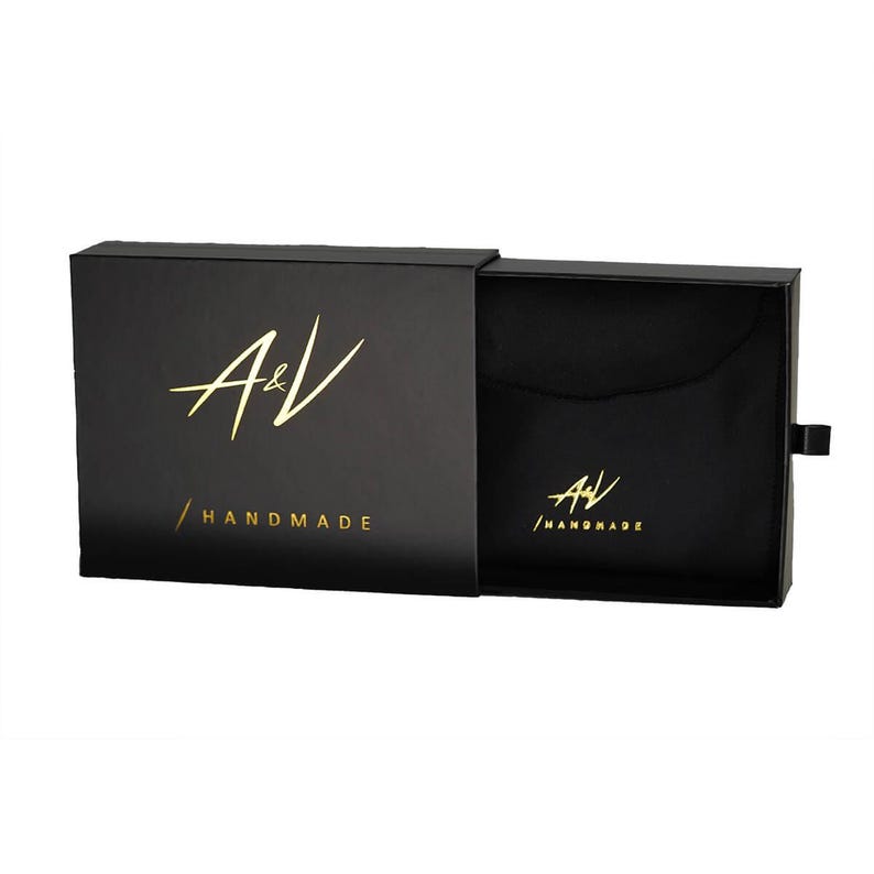 May include: Black box with a gold A&V logo and the text "HANDMADE". The box is open and the inside is lined with black fabric.