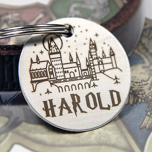 May include: Silver dog tag with a black engraved image of Hogwarts castle and the name "HAROLD".