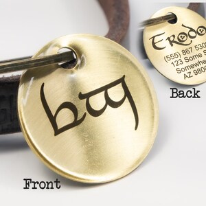 May include: Brass dog tag with a black inscription of the word "bag" on the front and contact information for "Erodo" on the back.