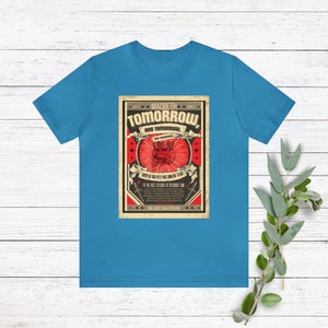 May include: A blue t-shirt with a vintage-style graphic featuring a red heart with a crown and the text "MACBETH TOMORROW AND TOMORROW, CREeps IN THIS PETTY PACE FROM DAY TO DAY... TO THE LAST SYLLABLE OF RECORDED TIME... WILLIAM SHAKESPEARE".