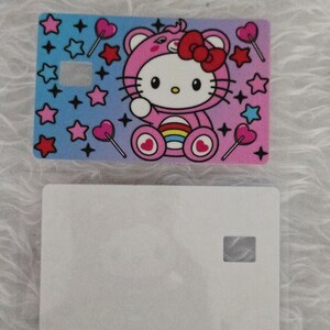 May include: Two rectangular cards. The top card features a colorful design with a cartoon cat in a pink outfit, surrounded by stars and heart-shaped lollipops. The bottom card is plain white.