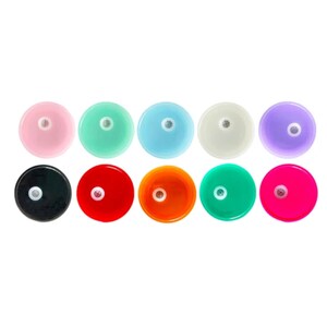 Op de afbeelding: Tien ronde flessenstoppers in verschillende kleuren, waaronder roze, lichtblauw, lichtgroen, wit, paars, zwart, rood, oranje, groen en felroze.
