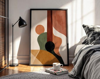 May include: Abstract art print of a guitar in shades of orange, green, and black, framed in a black border. The artwork is displayed on a wooden floor, next to a black lamp and a bed with a gray blanket and pillow. A coffee cup and a book are in front of the artwork.