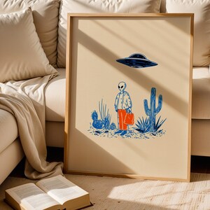 Retro alien UFO wall art featuring a quirky extraterrestrial walking through a desert landscape with cactus plants under a hovering spaceship. Bold blue and orange accents add a playful modern touch to the minimalist sci-fi illustration. Perfect for game rooms, living rooms, or offices, this unique artwork brings humor, character, and a creative sci-fi vibe to any interior. Ideal for space lovers and geek decor.