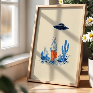 Retro alien UFO wall art featuring a quirky extraterrestrial walking through a desert landscape with cactus plants under a hovering spaceship. Bold blue and orange accents add a playful modern touch to the minimalist sci-fi illustration. Perfect for game rooms, living rooms, or offices, this unique artwork brings humor, character, and a creative sci-fi vibe to any interior. Ideal for space lovers and geek decor.
