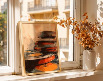 May include: A framed art print featuring a stack of vinyl records in shades of orange, red, and black. The artwork is set against a warm, neutral background, with a light wooden frame. The print is displayed on a windowsill.