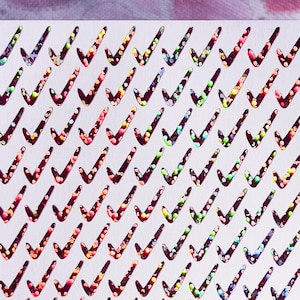 May include: White card with a repeating pattern of check marks. Each check mark is filled with iridescent glitter in shades of pink, blue, green, and purple.