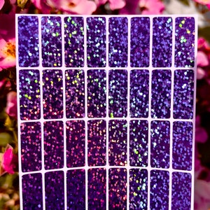 May include: A sheet of purple iridescent glitter stickers with 24 individual stickers. Each sticker is rectangular and has a white border.