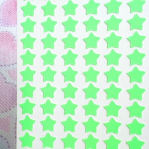May include: A sheet of bright green star-shaped stickers arranged in a grid pattern. The stickers are evenly spaced on a white background. The stickers are a vibrant, eye-catching green color.