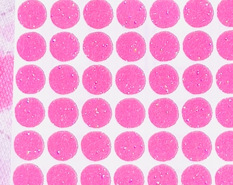 May include: A sheet of circular stickers in a bright pink color with a textured surface and embedded iridescent glitter particles. The stickers are arranged in a grid pattern on a white backing sheet, each featuring a consistent round shape.