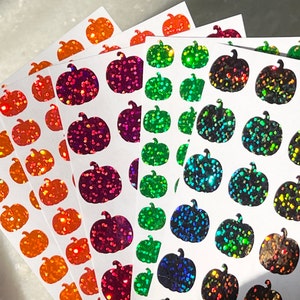 May include: Sheets of stickers with various colors of glitter pumpkins. The stickers are on white sheets and are ready to be used for crafts or decorating.