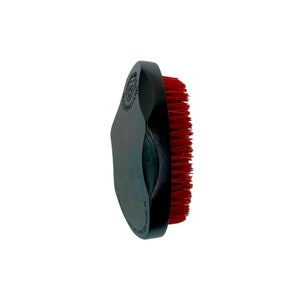 May include: A black brush with red bristles. The brush has a curved handle and a rounded head. The text "30 MILLION" and other text is visible on the handle. The brush is designed for grooming.