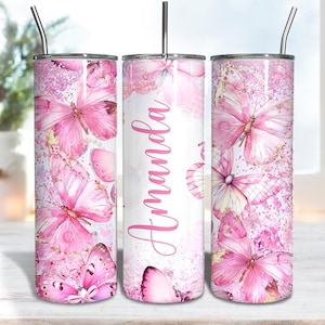 May include: A pink tumbler with a butterfly design. The tumbler features pink butterflies and the name "Amanda" in a pink script. It has a silver lid and a silver straw.