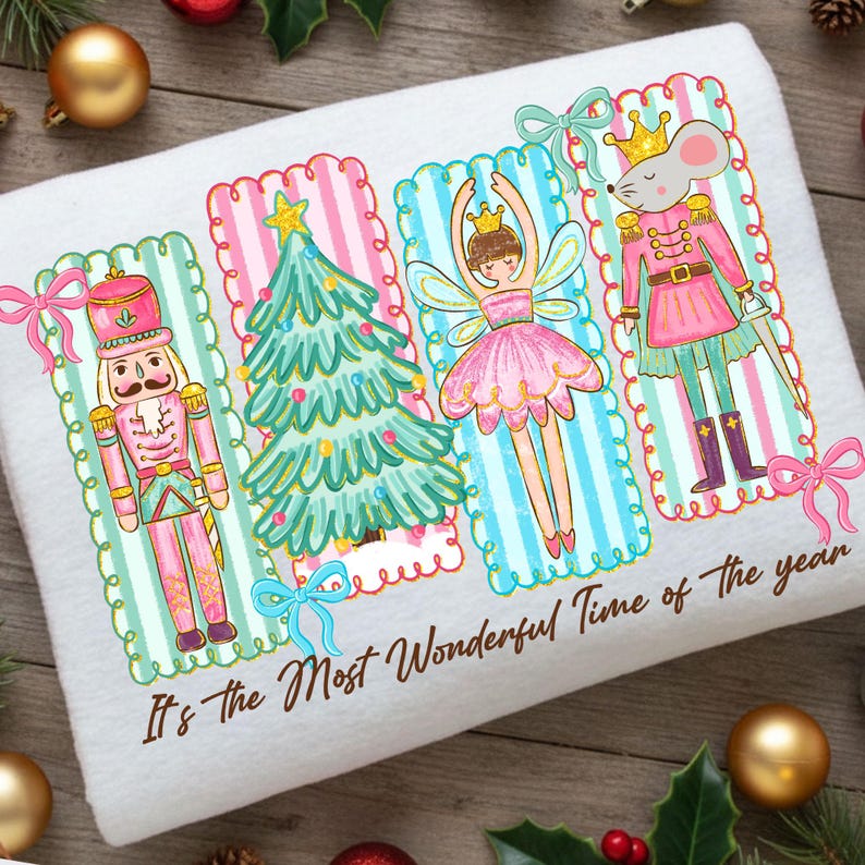 May include: White towel featuring a festive design with a nutcracker, Christmas tree, fairy, and mouse in pink, green, and blue. The text "It's the Most Wonderful Time of the year" is printed at the bottom. Decorative bows and gold ornaments surround the towel.