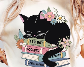 May include: A white t-shirt with a black cat sleeping on a stack of books. The books are titled "Law Boy", "Forever", "The Runner", and "Of Mice and Men". The cat is surrounded by pink, white, and blue flowers.