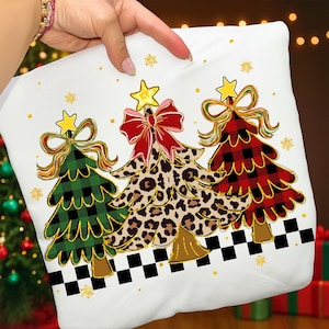 May include: White pillowcase featuring three Christmas trees with star toppers and bows. The trees have plaid, leopard print, and green patterns. Gold snowflakes and a black and white checkered border complete the festive design.