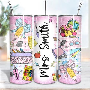 May include: A pink glitter tumbler with a teacher theme. The tumbler features school supplies like pencils, pens, and a backpack. The name "Mrs. Smith" is written on the tumbler.