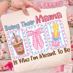 May include: A cream cushion with the text "Being Their Mama Is Who I'm Meant To Be." The design includes illustrations of a coffee, a pink bow, and fries, all within decorative frames, in shades of pink and blue.