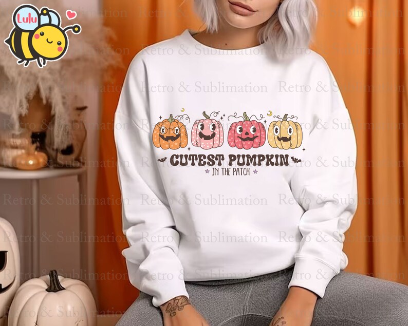 Może przedstawiać: Biała bluza z nadrukiem czterech uśmiechniętych dyni i tekstem "Cutest Pumpkin in the Patch".