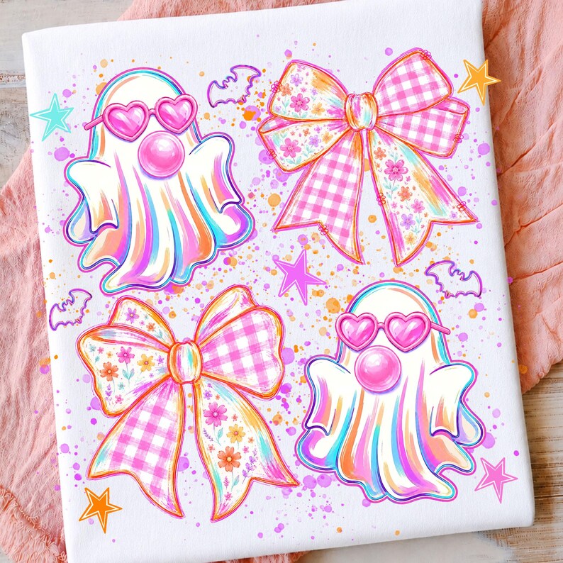 May include: A white fabric surface featuring a colorful graphic print of two ghosts wearing pink heart-shaped sunglasses and blowing bubblegum, two large bows with pink gingham and floral patterns, small bats, and scattered stars.