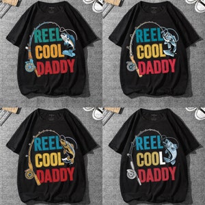 May include: Black t-shirts with the text "REEL COOL DADDY" in teal, yellow, and red. The design includes a fishing rod and a fish. The shirts are short-sleeved.