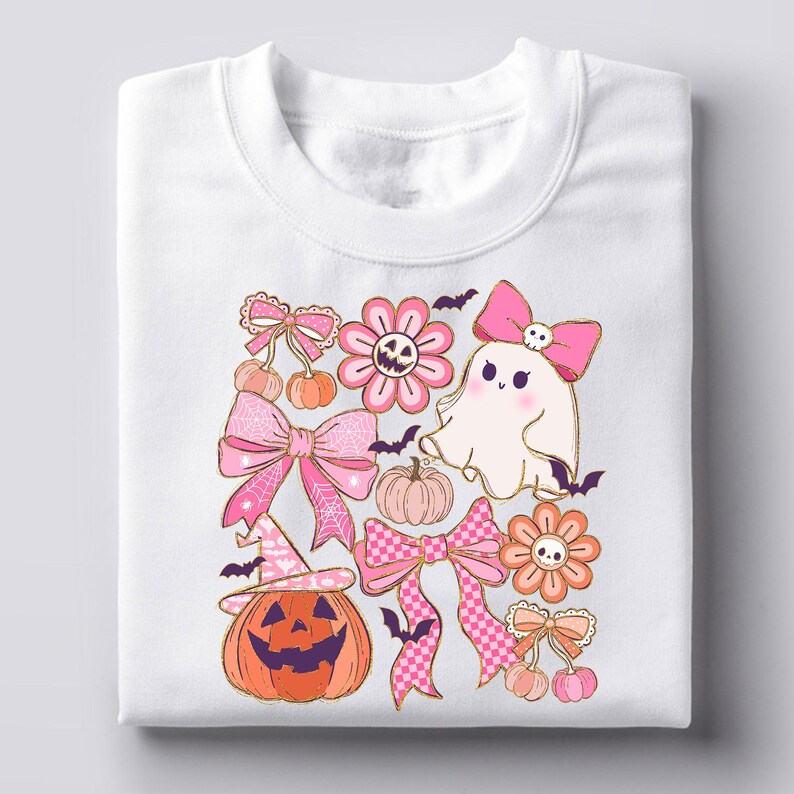 May include: White sweatshirt featuring a colorful Halloween-themed design. The design includes a smiling jack-o'-lantern, pink bows, flowers, a ghost, pumpkins, bats, and cherries. The graphics are in shades of pink, orange, and gold.