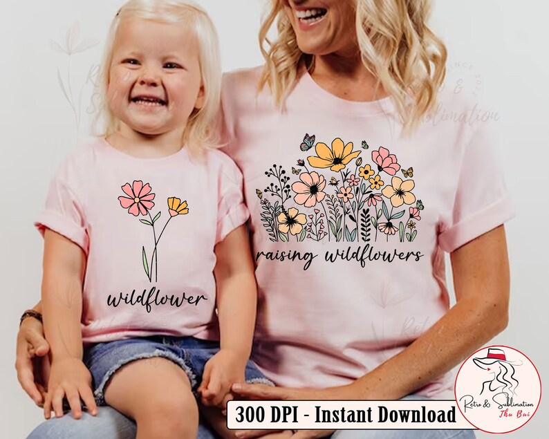 May include: Two pink t-shirts with a floral design and the text "raising wildflowers" and "wildflower".