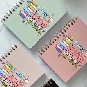Puede incluir: Tres cuadernos de espiral con una cubierta rosa, verde y beige. Cada cuaderno tiene un gr&aacute;fico colorido de una pila de libros y una taza de caf&eacute; helado con el texto "Nac&iacute; para leer y beber caf&eacute; helado".