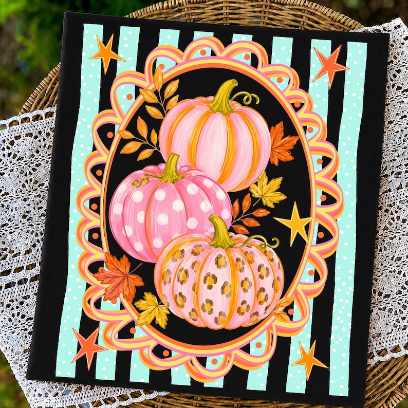 May include: A rectangular wall art piece featuring three pumpkins in pink and orange tones. One pumpkin has white polka dots, one has a leopard print, and one is solid. They are framed by an oval border with orange stars on a black and teal striped background.