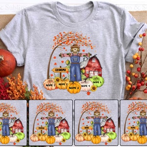 May include: A gray t-shirt with a fall-themed design featuring a scarecrow, a red barn, pumpkins, and fall leaves. The design includes the text "Grandma", "Name 1", "Name 2", "Name 3", "Name 4", and "Name 5".