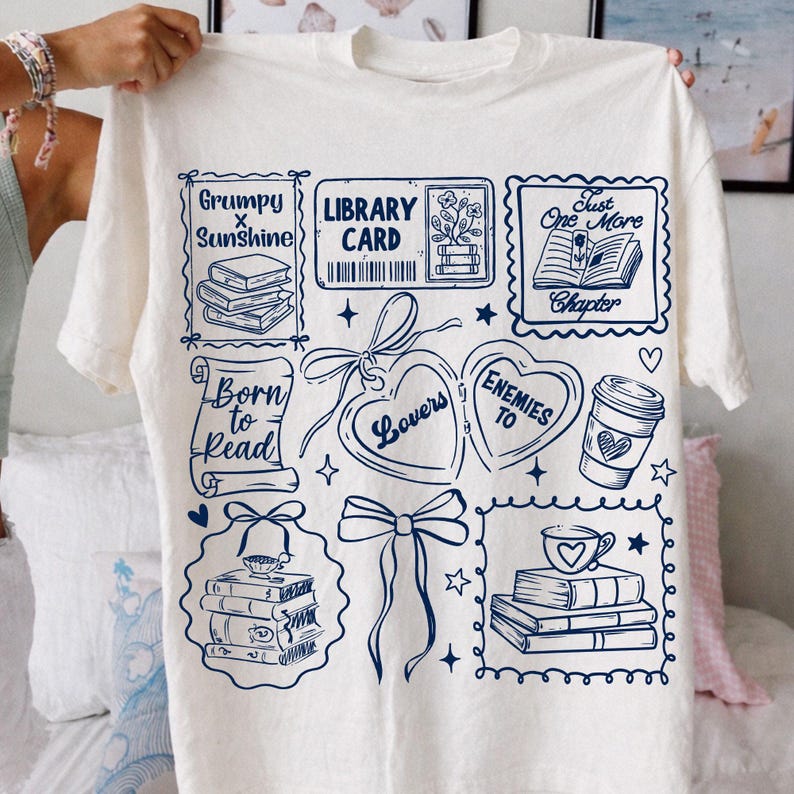 Puede incluir: Camiseta de color crema con un dise&ntilde;o gr&aacute;fico azul marino que presenta ilustraciones tem&aacute;ticas de libros y texto. El dise&ntilde;o incluye frases como "Grumpy x Sunshine", "Library Card" y "Born to Read". La camiseta es una prenda informal.