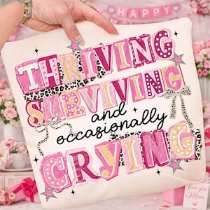 May include: Cream-colored throw pillow with the words "Thriving, Surviving, and occasionally Crying" in pink, yellow, and black lettering. The design includes star and bow accents with a leopard print pattern.