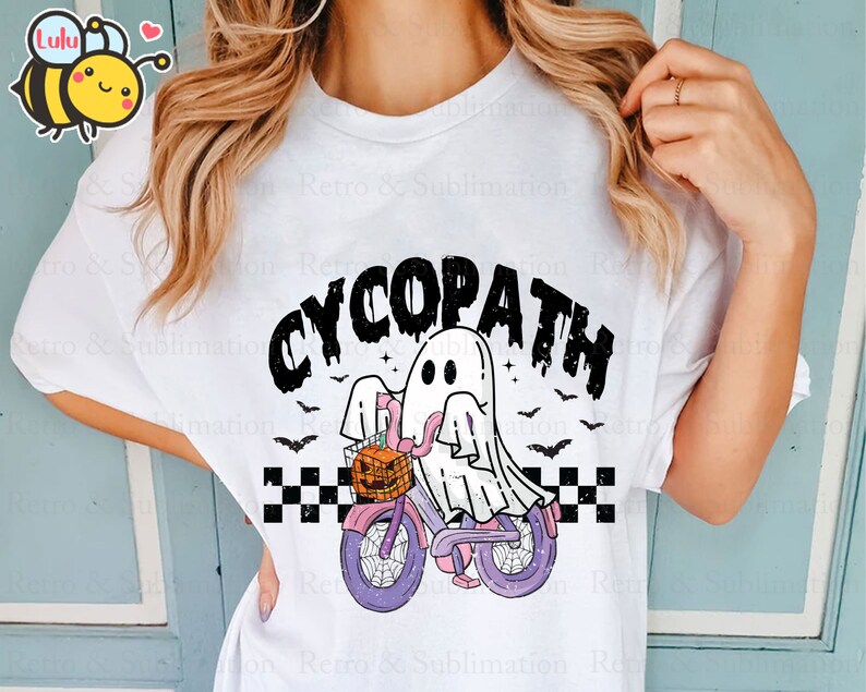May include: White t-shirt with a black and white graphic of a ghost riding a bicycle with a pumpkin basket. The text "CYCOPATH" is above the ghost.