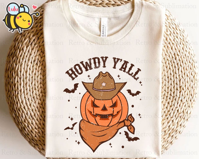 May include: A white t-shirt with the text "Howdy Y'all" in brown lettering. A cartoon pumpkin wearing a cowboy hat is in the centre of the shirt. The pumpkin is orange with a brown hat and a brown bandana.