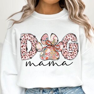 May include: White sweatshirt with a pink and brown floral paw print design and the text "Dog mama" printed on the front.