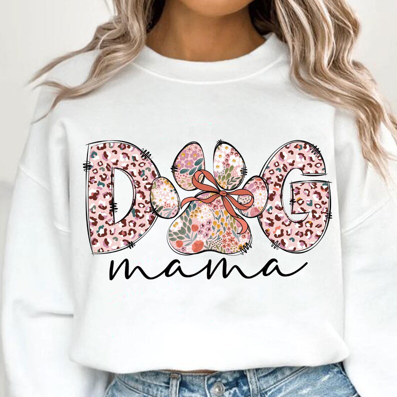 May include: White sweatshirt with a pink and brown floral paw print design and the text "Dog mama" printed on the front.