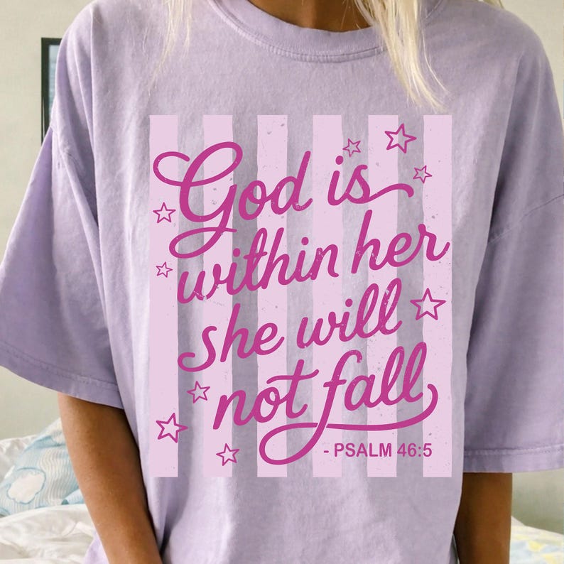 May include: A light purple t-shirt with the text "God is within her she will not fall - Psalm 46:5" in pink script. The design includes pink vertical stripes and star accents.