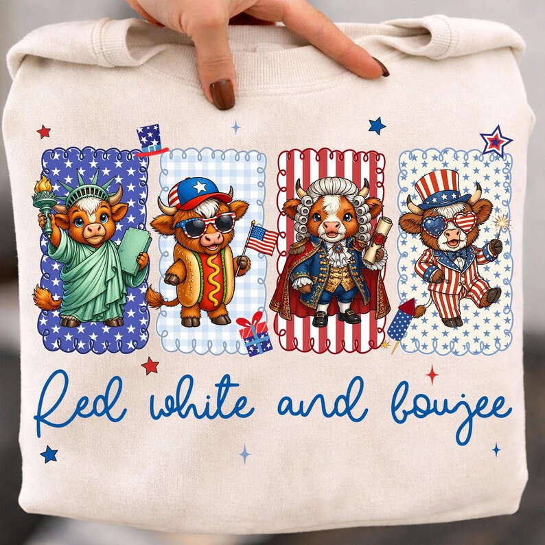 May include: A cream-colored sweatshirt featuring four cartoon cows dressed in patriotic attire. The cows are depicted as the Statue of Liberty, a hot dog, a historical figure, and a Fourth of July celebrant. The text "Red white and boujee" is written in blue script.