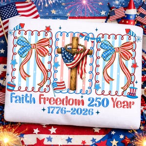 Może przedstawiać: Biała bluza z patriotycznym wzorem. Zawiera krzyż z flagą USA, dwie ilustracje kokard i napis "Faith Freedom 250 Year +1776-2026+" w kolorze czerwonym i niebieskim. Uzupełniona gwiazdami, paskami i fajerwerkami.