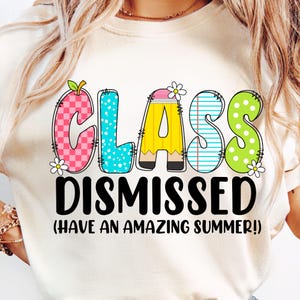 May include: White t-shirt with the text "Class Dismissed (Have an Amazing Summer!)" in black. The word "Class" is in colorful, playful letters with a pencil, apple, and polka dots.