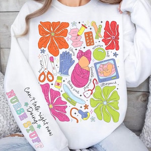 May include: White sweatshirt with a colorful graphic design featuring a baby, flowers, and medical tools. The text "Can't talk right now Doing NURSE STUFF" is on the sleeve.