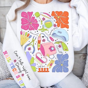 May include: White sweatshirt with a colorful design featuring nail art tools, flowers, and the text "Can't talk right now *Doing Nail Tech Stuff*"