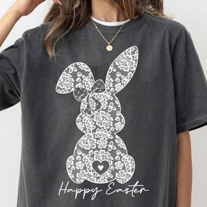 May include: A gray t-shirt with a white lace bunny design and the text "Happy Easter".