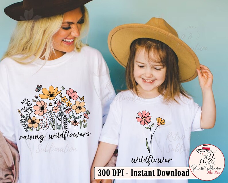 May include: Two white t-shirts with a floral design. The larger shirt has the text "raising wildflowers" and the smaller shirt has the text "wildflower".