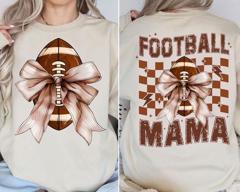Op de afbeelding: Een beige sweatshirt met een bruine voetbal die is vastgebonden met een bruine strik. De tekst "FOOTBALL MAMA" is gedrukt op de achterkant van het sweatshirt met een bruin geruit patroon.